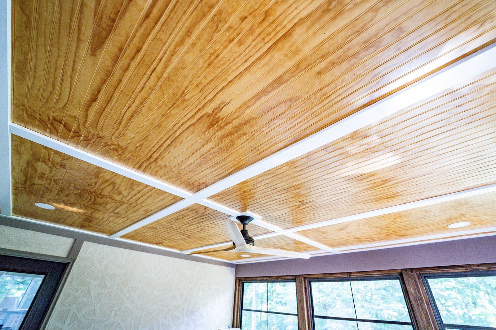 A wooden ceiling with a ceiling fan in a room.