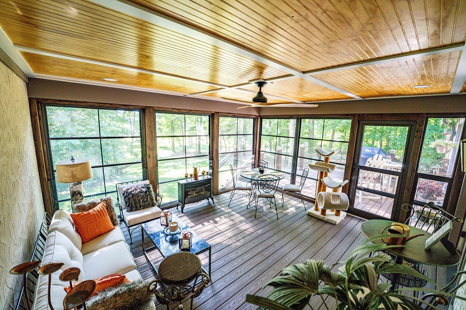 A screened in porch with a lot of windows and furniture.