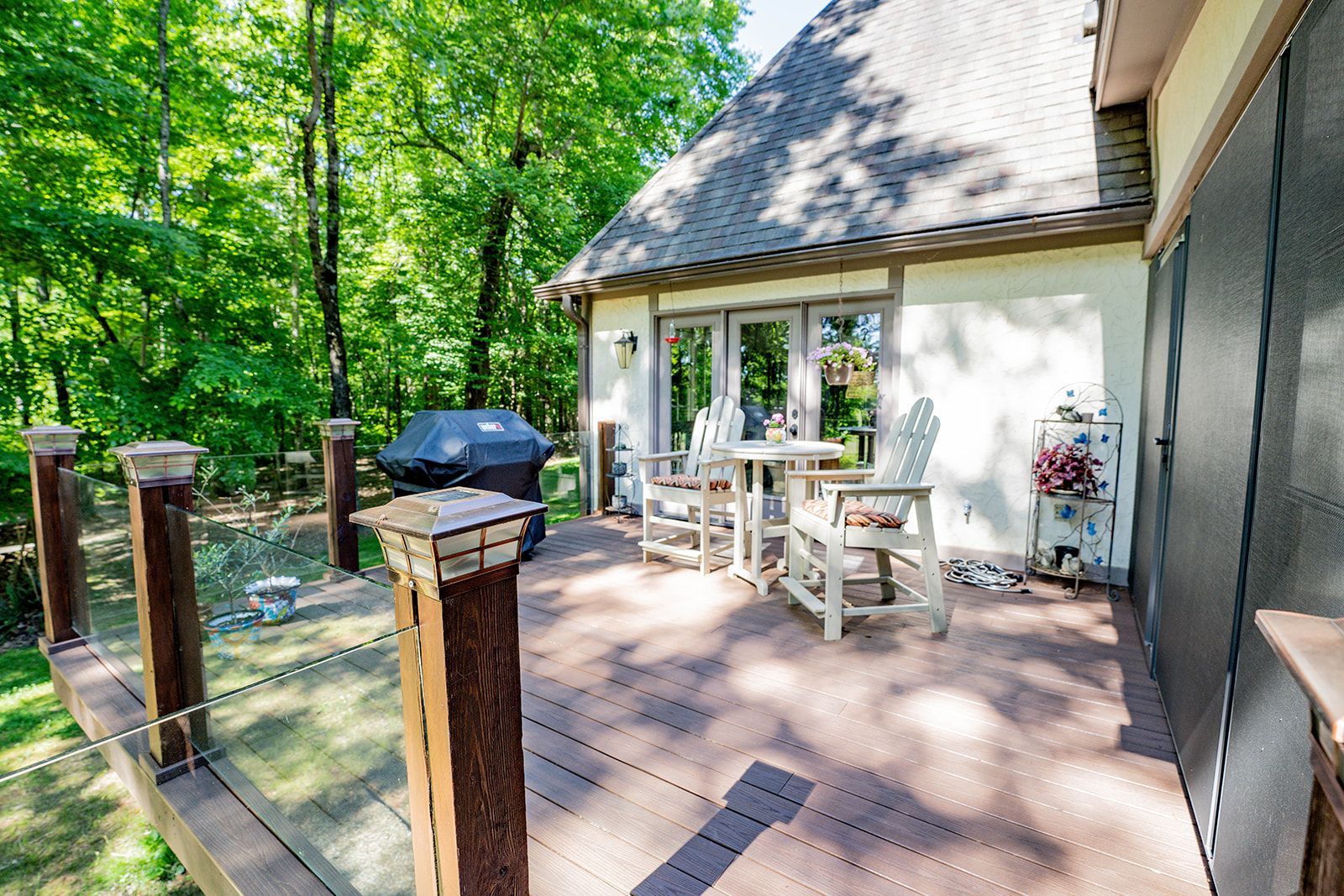 There is a deck with a table and chairs on it in front of a house.
