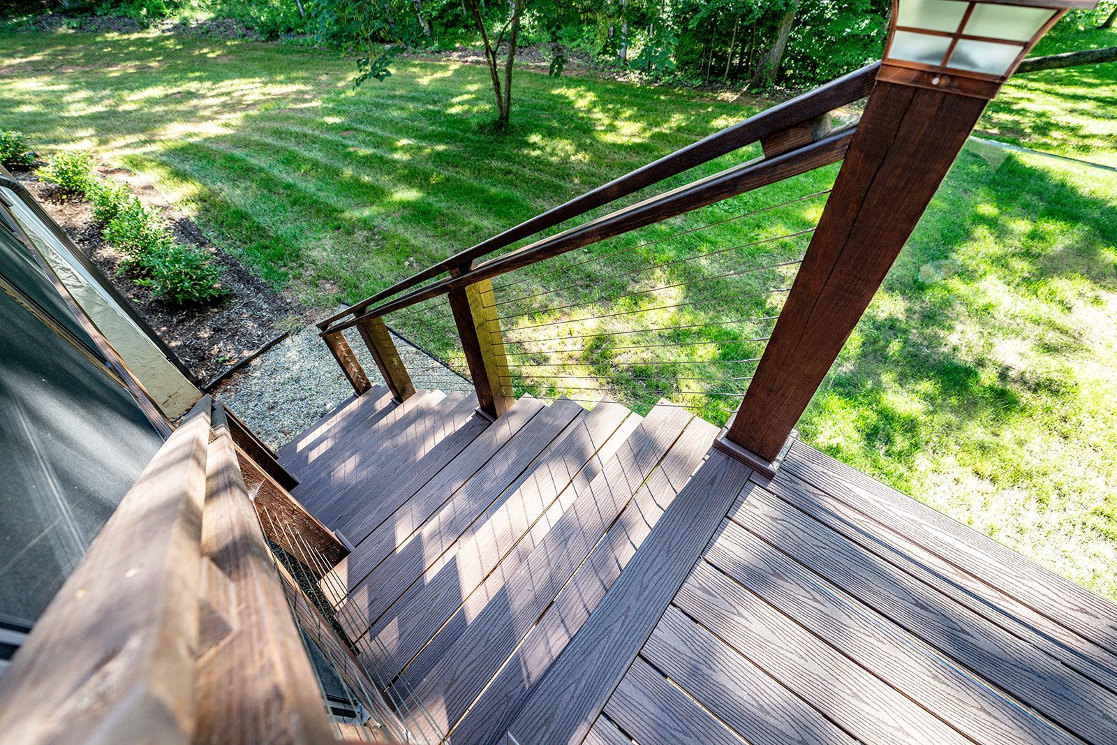 A wooden deck with stairs leading up to a grassy yard.