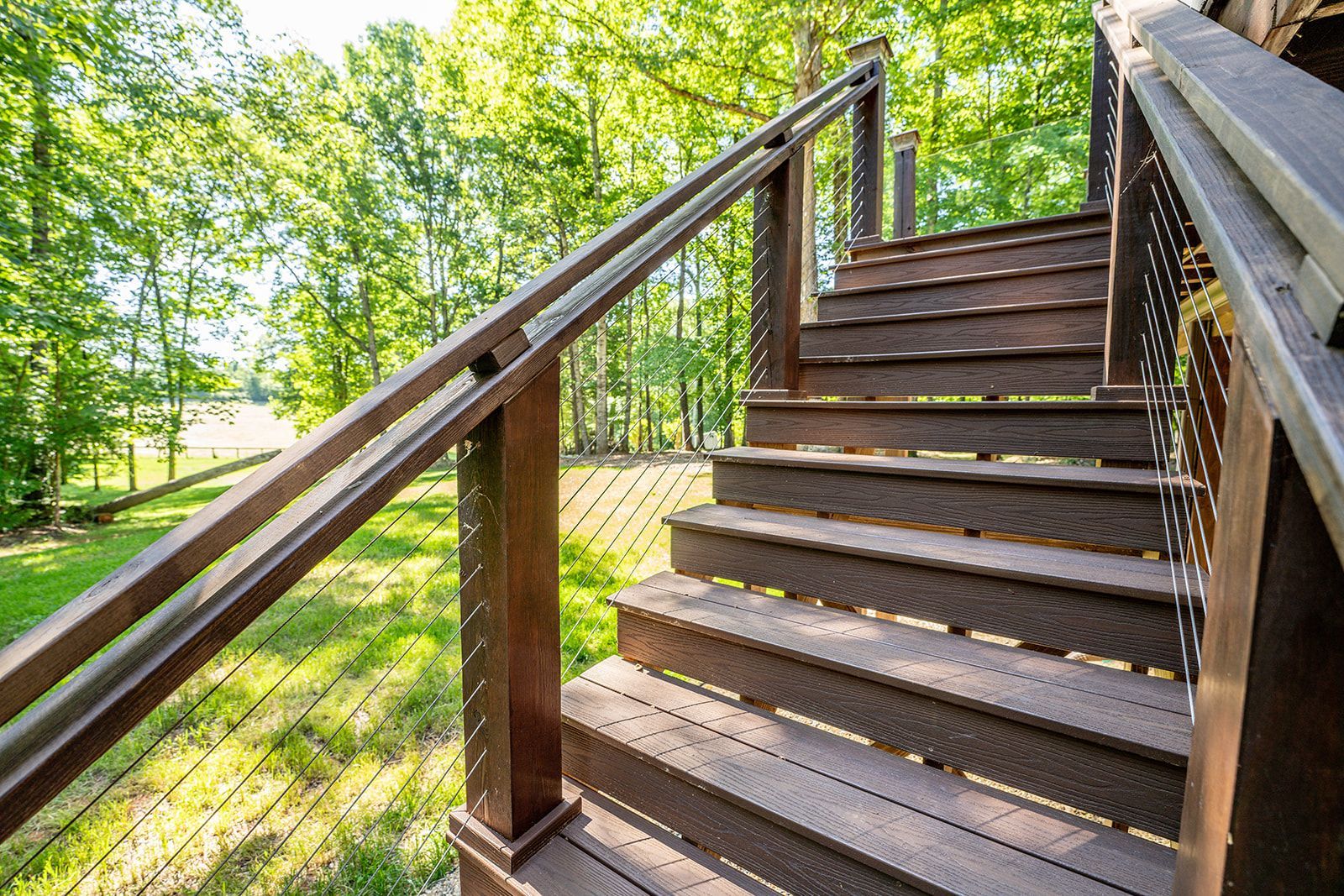 A wooden deck with stairs leading up to it and trees in the background.
