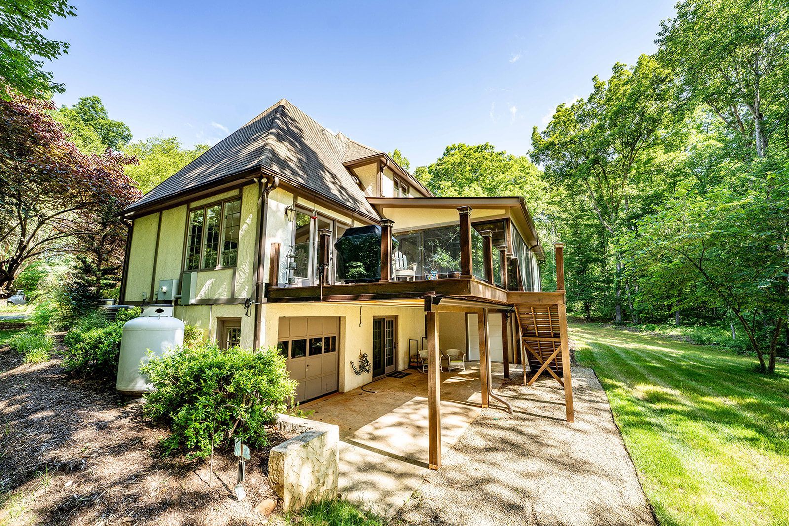 A large house with a lot of windows is surrounded by trees and grass.
