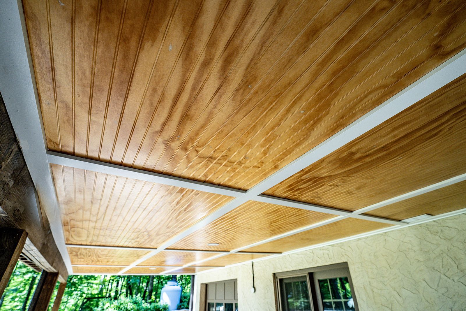 A wooden ceiling with a white trim on a porch.