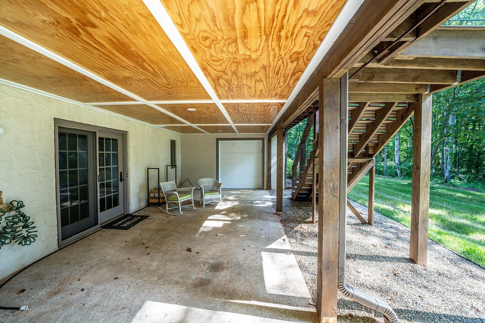 A large covered patio with a wooden deck and a garage door.