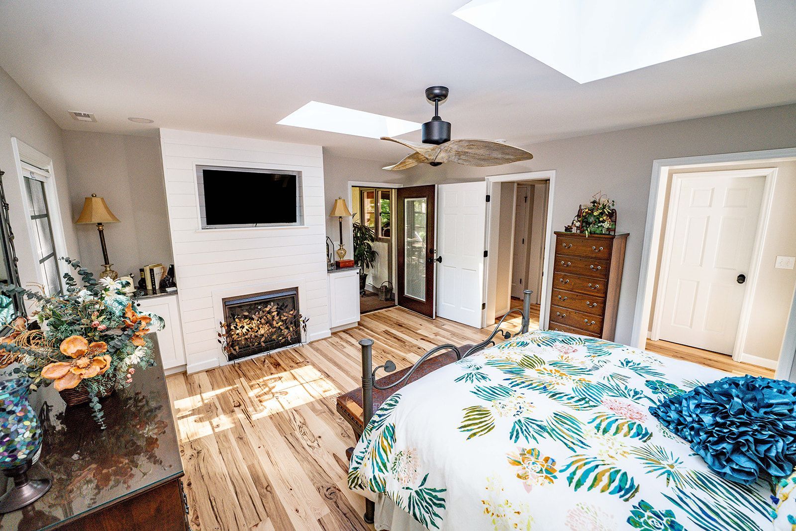 A bedroom with a bed , fireplace , television and skylight.