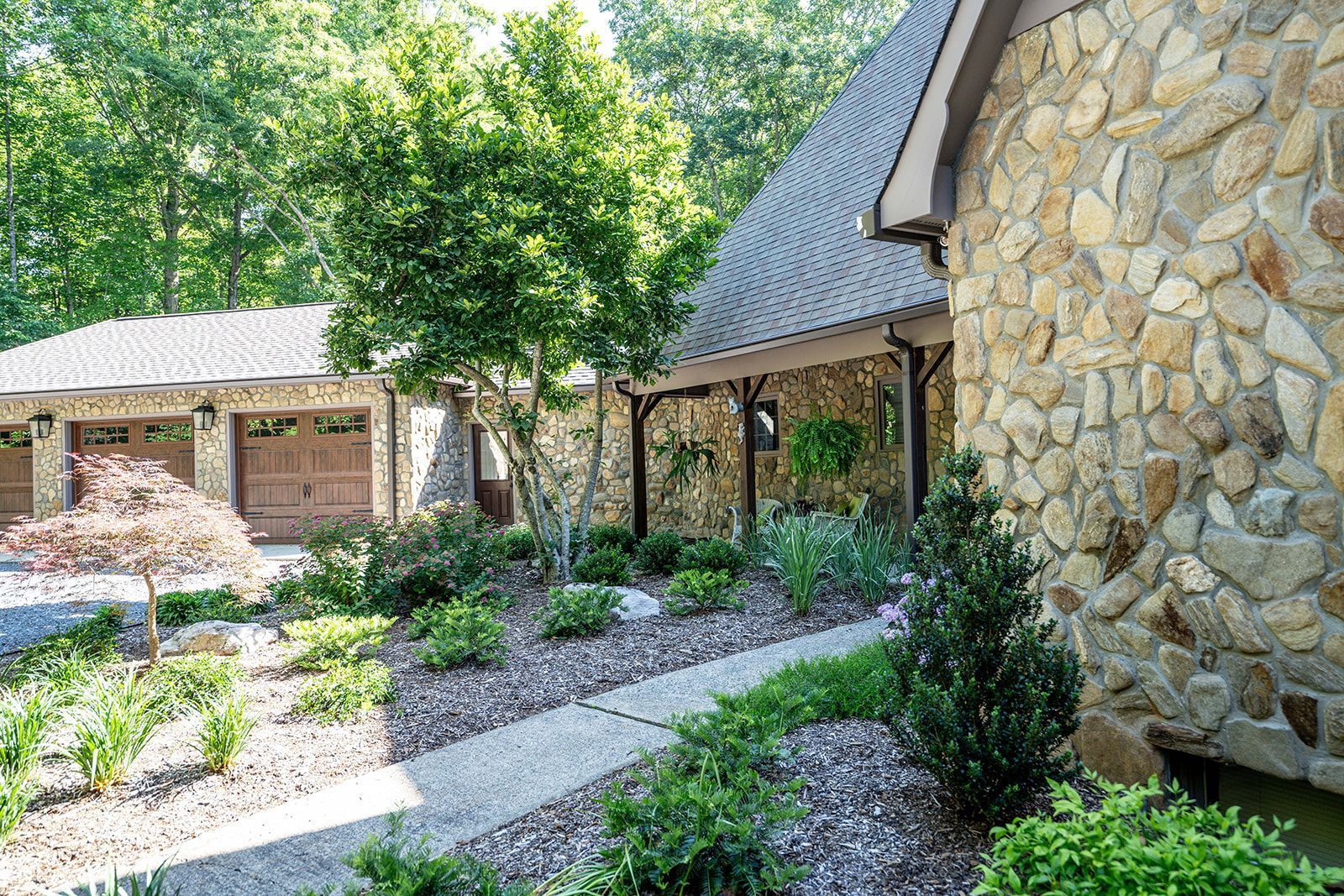 A house with a stone wall and a walkway leading to it.