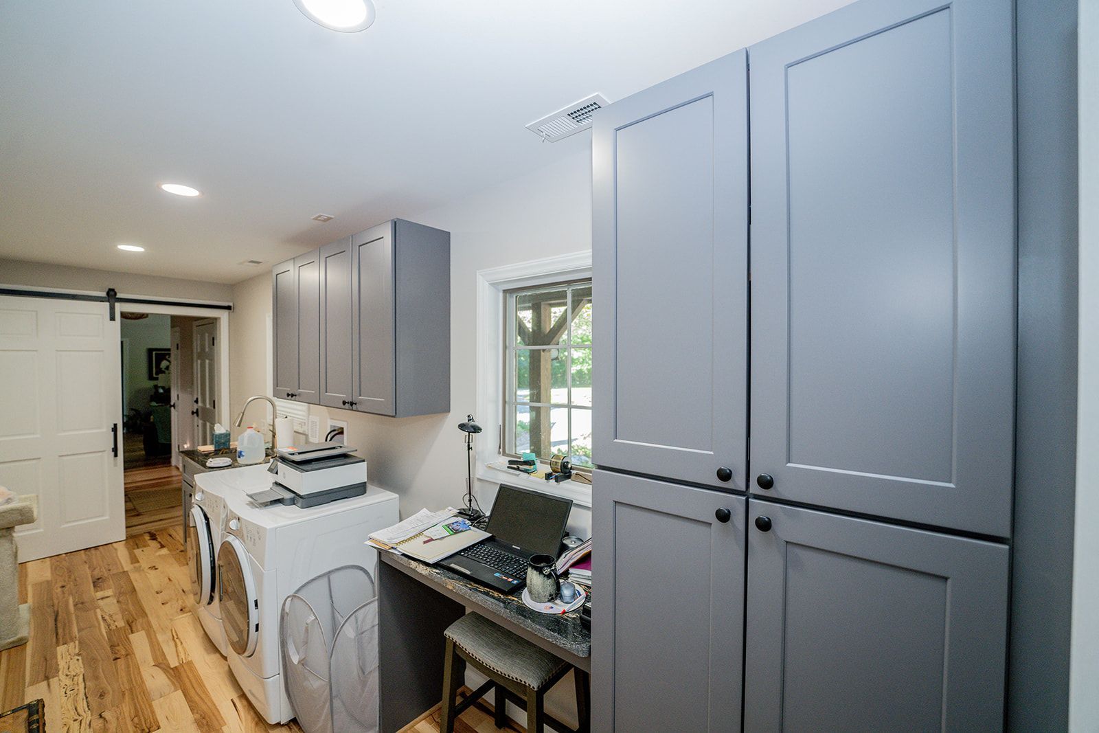A laundry room with a washer and dryer and a desk with a laptop on it.