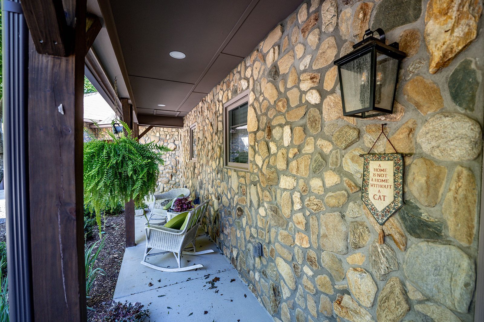 There is a rocking chair on the porch of a stone house.