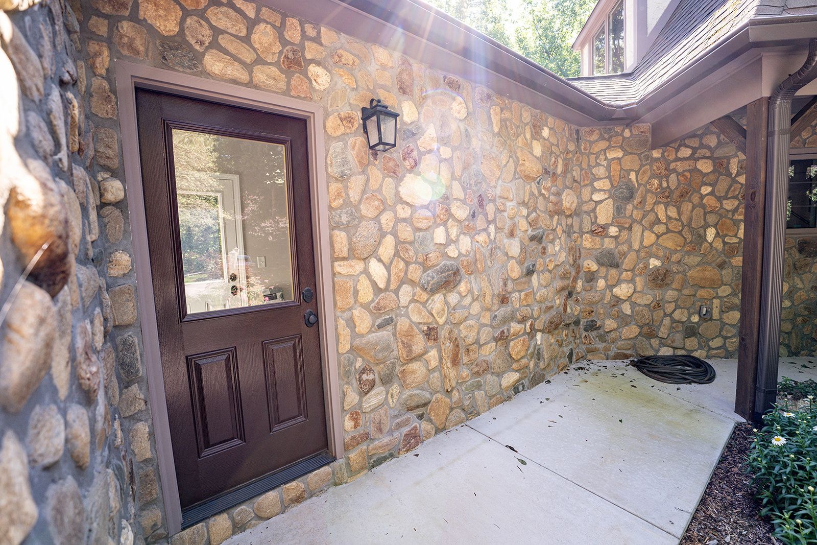 A stone wall with a brown door and a window.