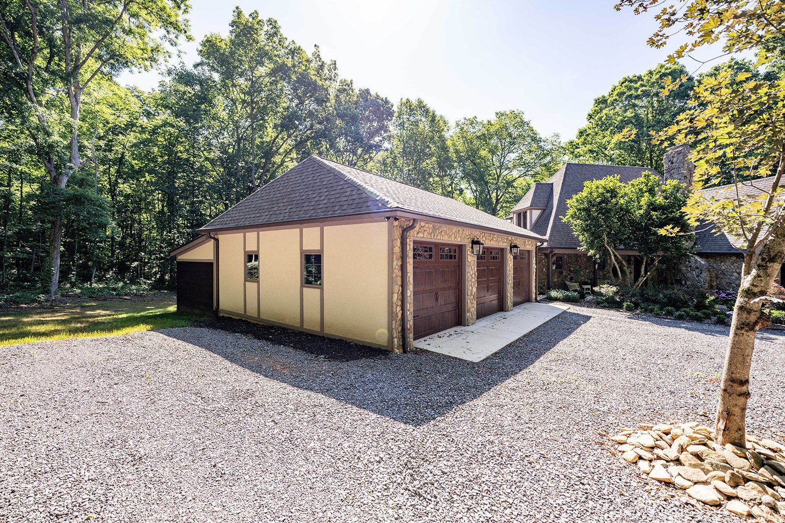 A large garage is sitting in the middle of a gravel driveway.