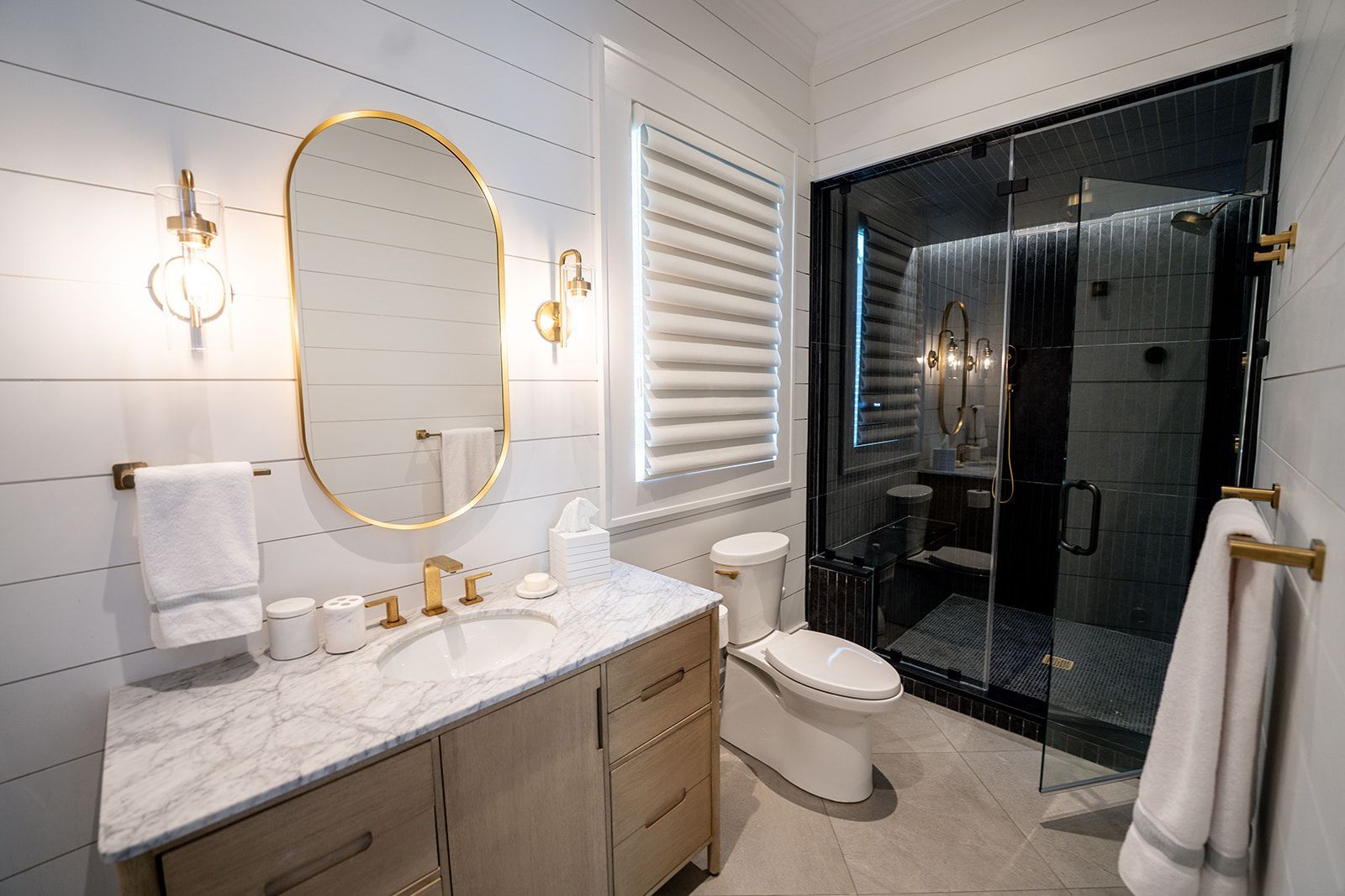 A bathroom with a toilet , sink , mirror and walk in shower.