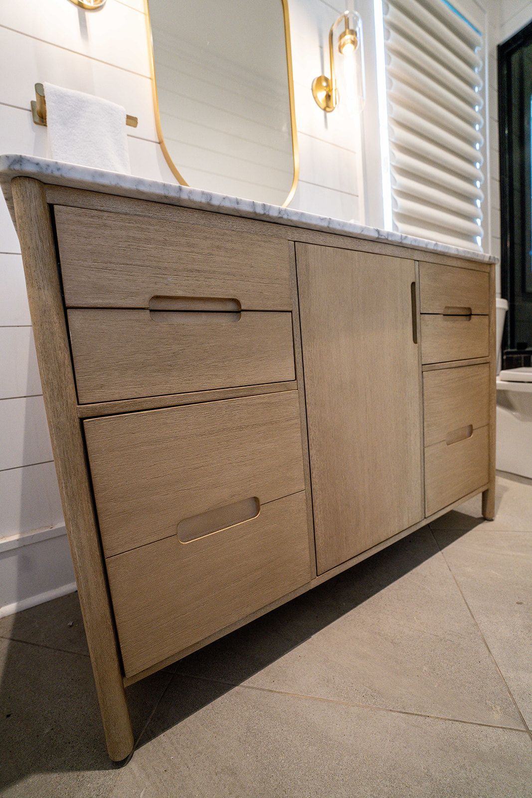 A bathroom vanity with drawers and a mirror.