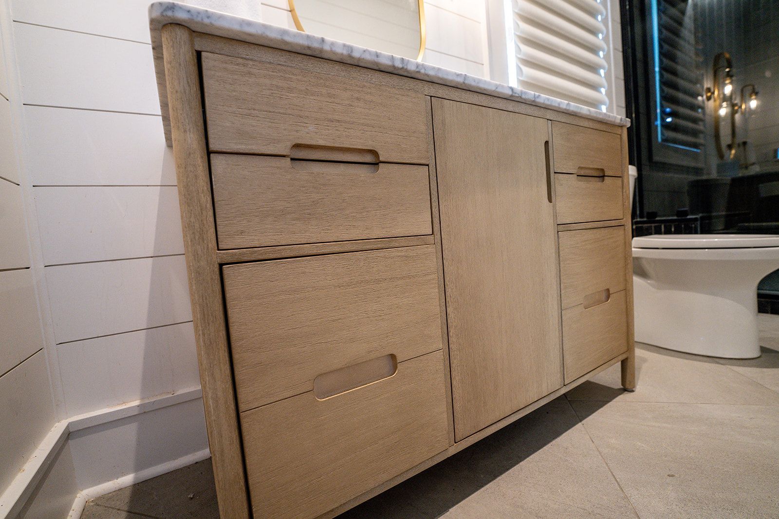 A bathroom vanity with drawers and a toilet in the background.