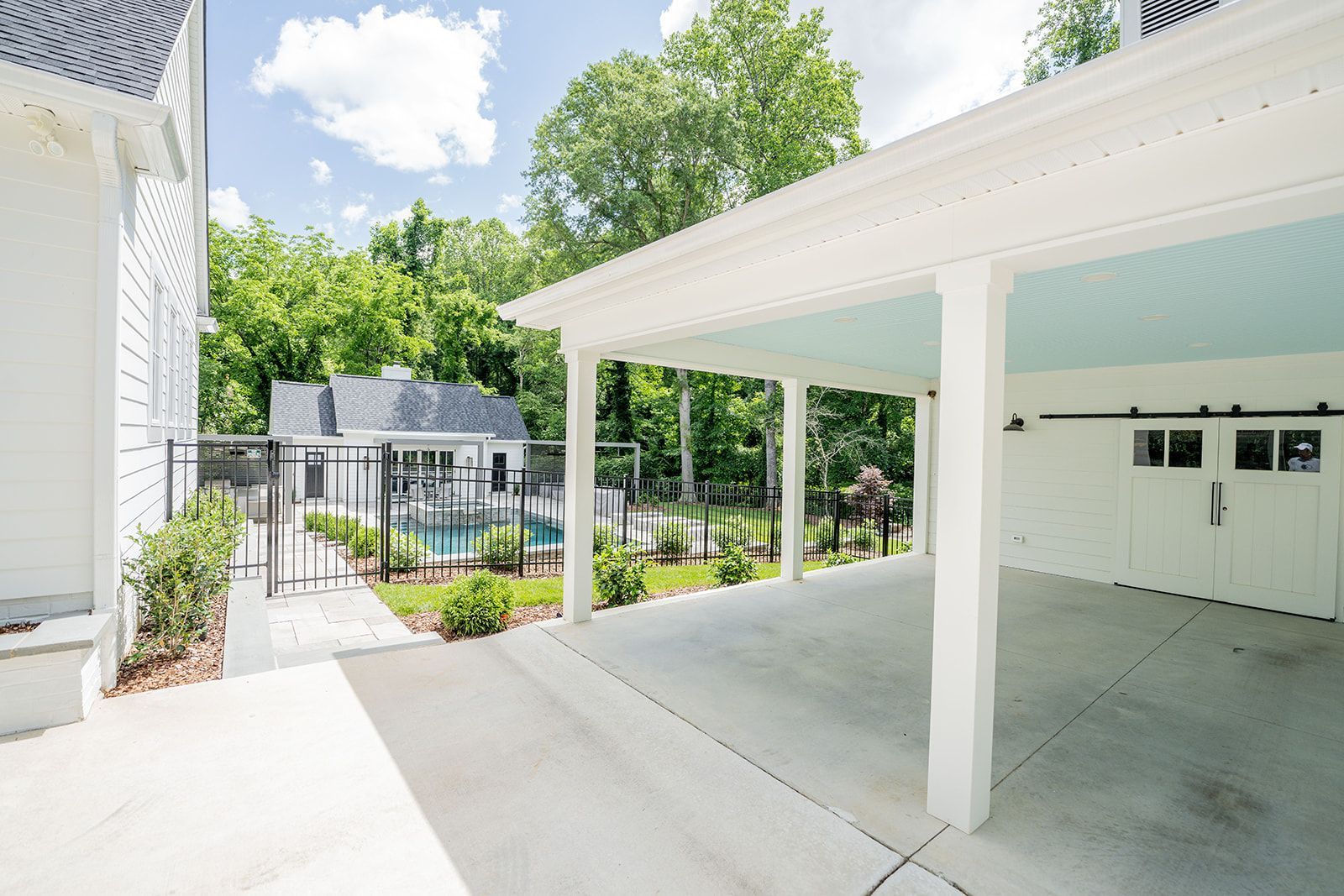 A white house with a garage and a pool in the backyard.