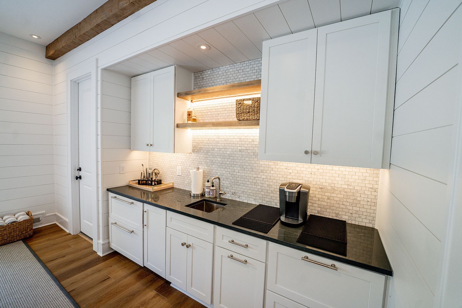 A kitchen with white cabinets , black counter tops , and a sink.