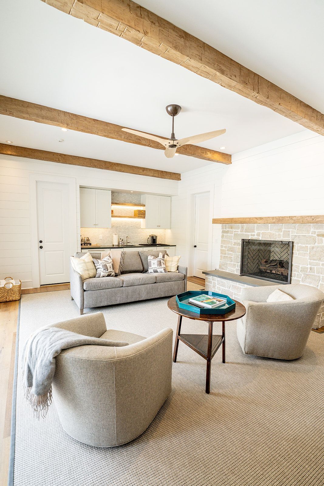 A living room with a couch , two chairs , a table and a fireplace.