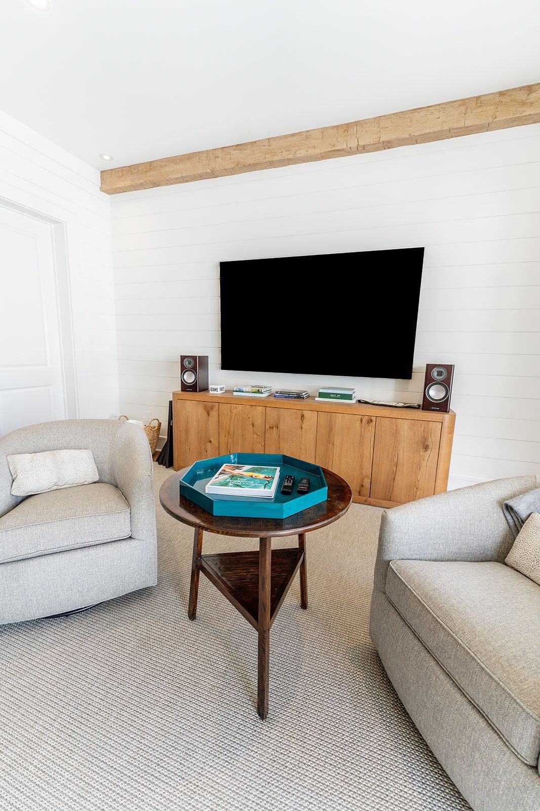 A living room with two chairs , a table , and a flat screen tv.