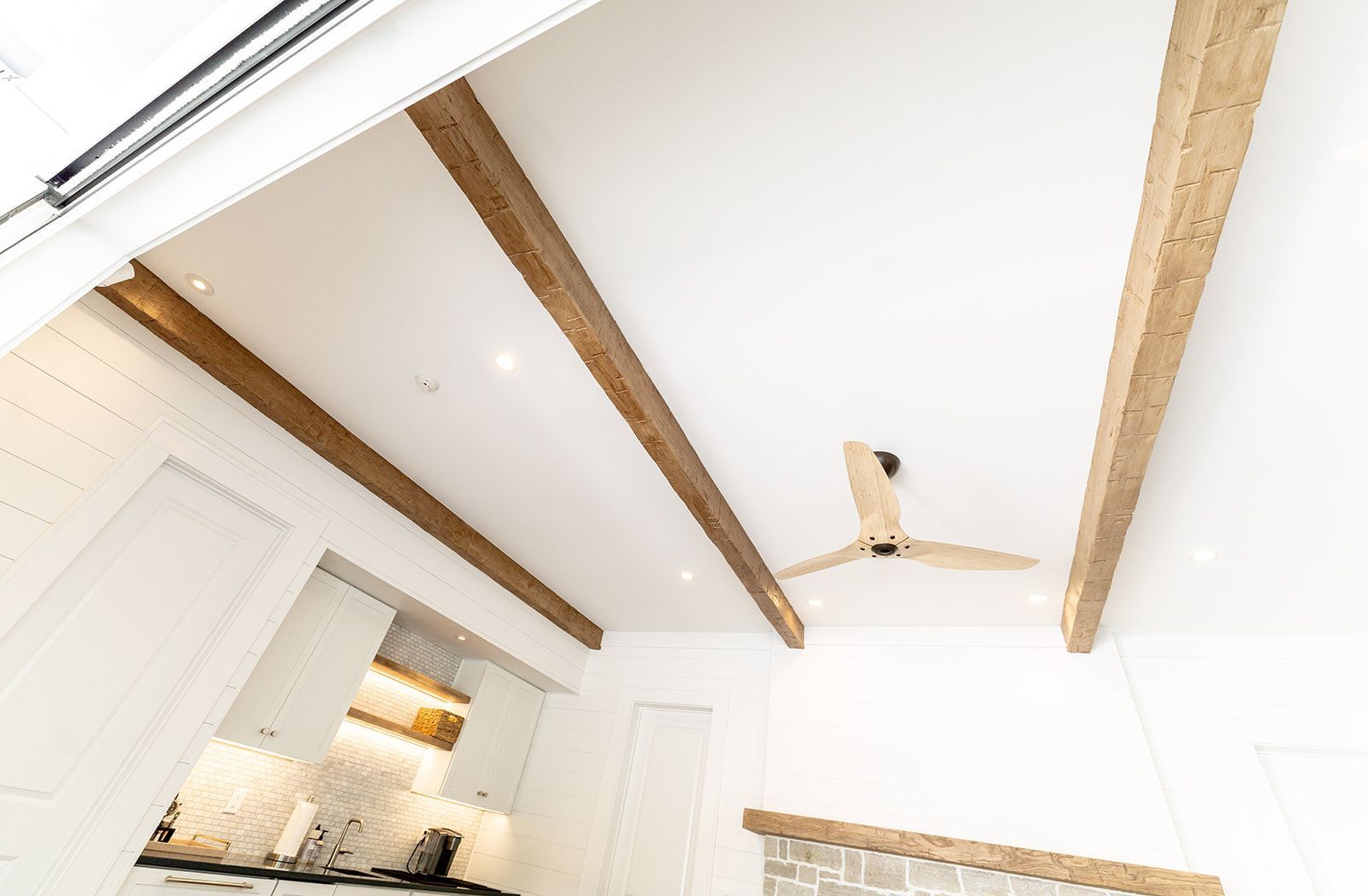 A kitchen with a ceiling fan and wooden beams.