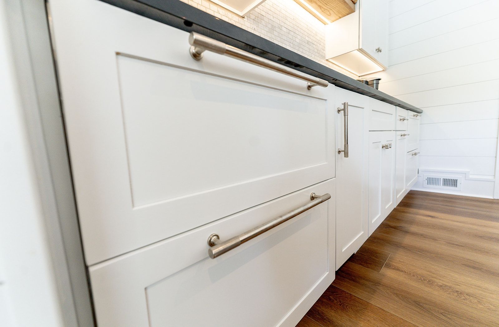 A kitchen with white cabinets and stainless steel handles.