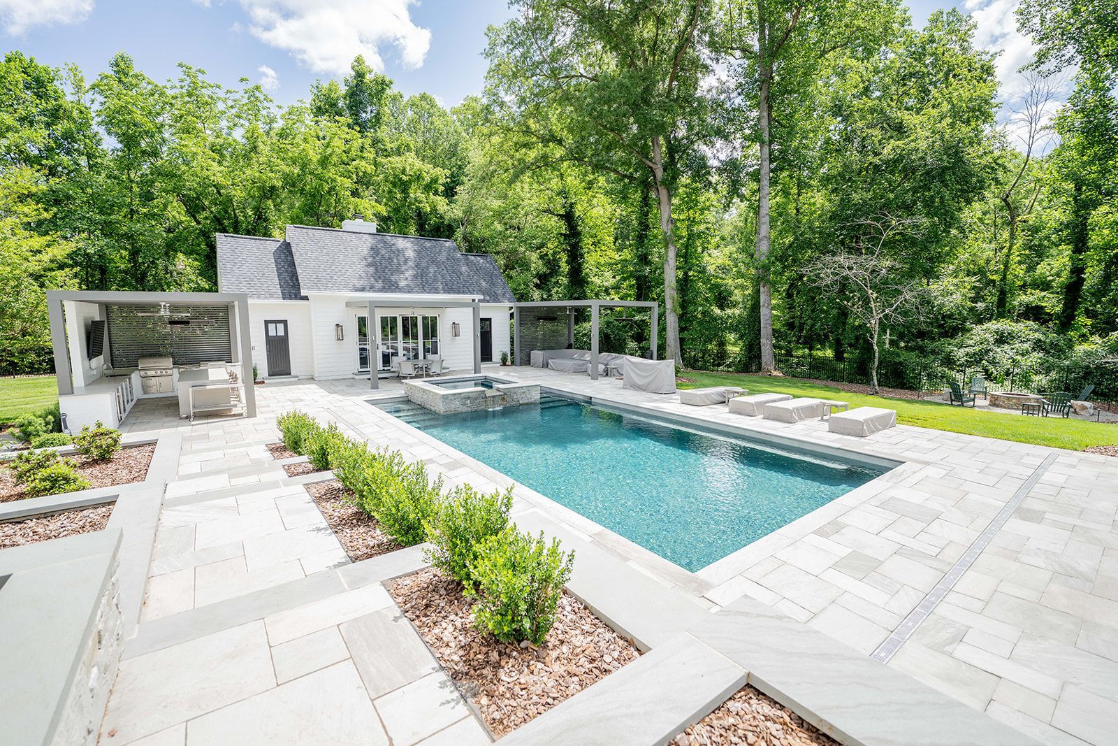 A large swimming pool in the backyard of a house surrounded by trees.