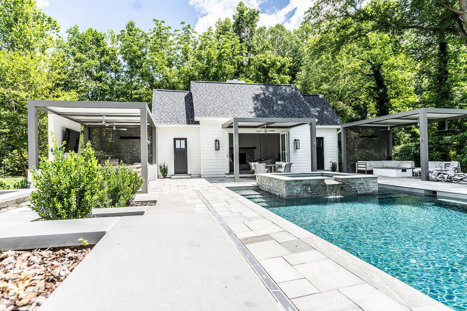 A white house with a large swimming pool in front of it.