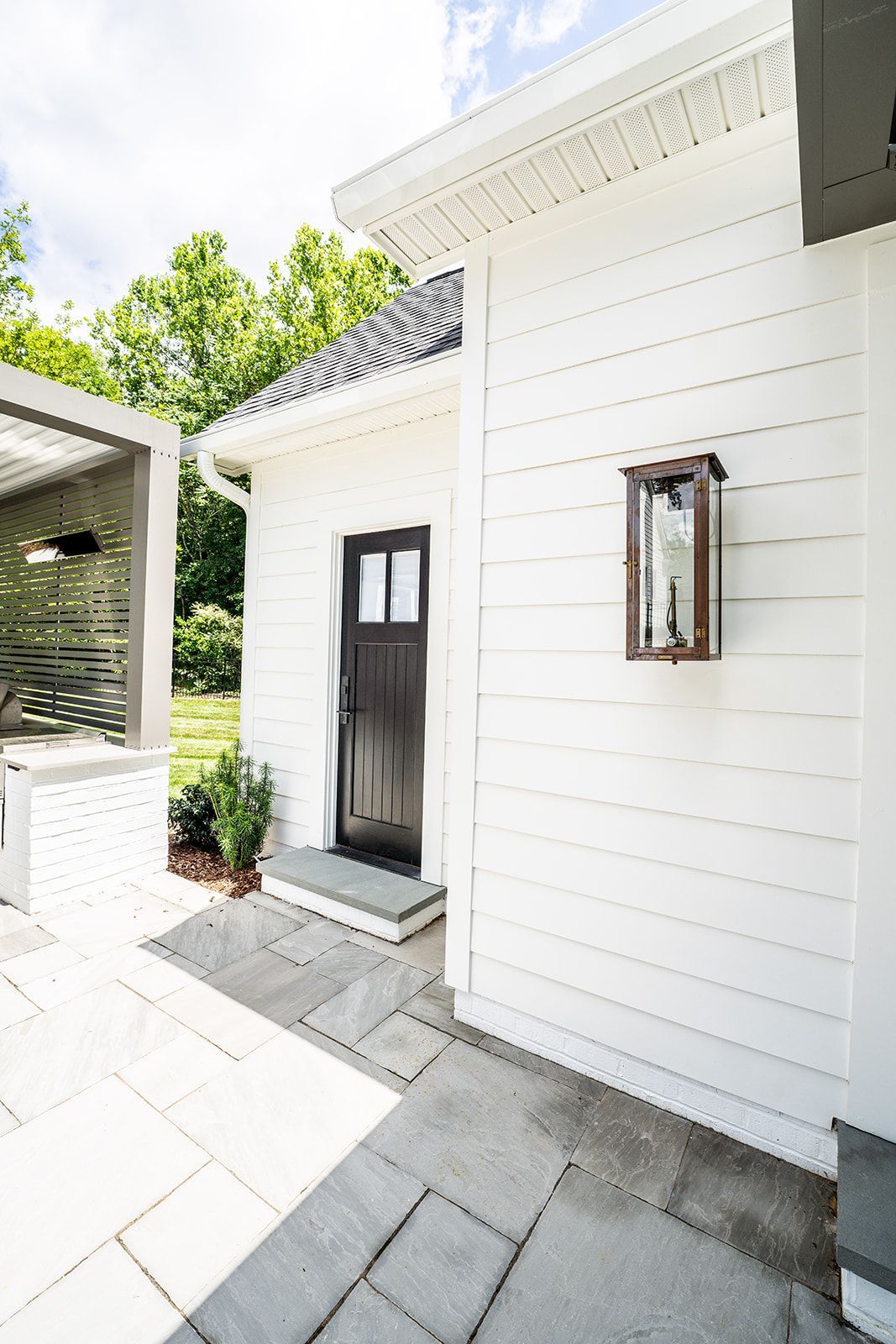 A white house with a black door and a lantern on the side.