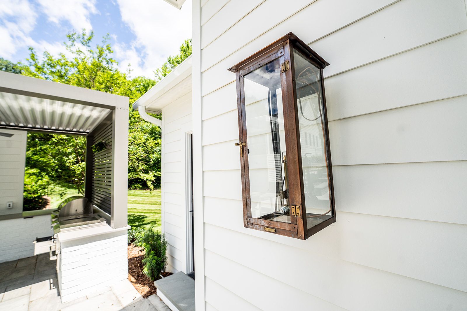 A lantern is hanging on the side of a white house.
