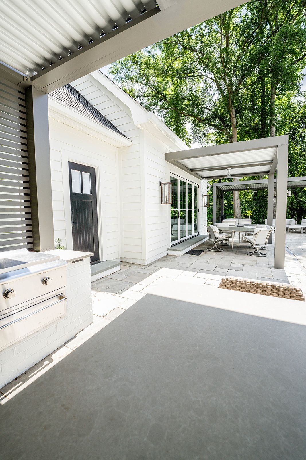 A white house with a patio area and a pergola.