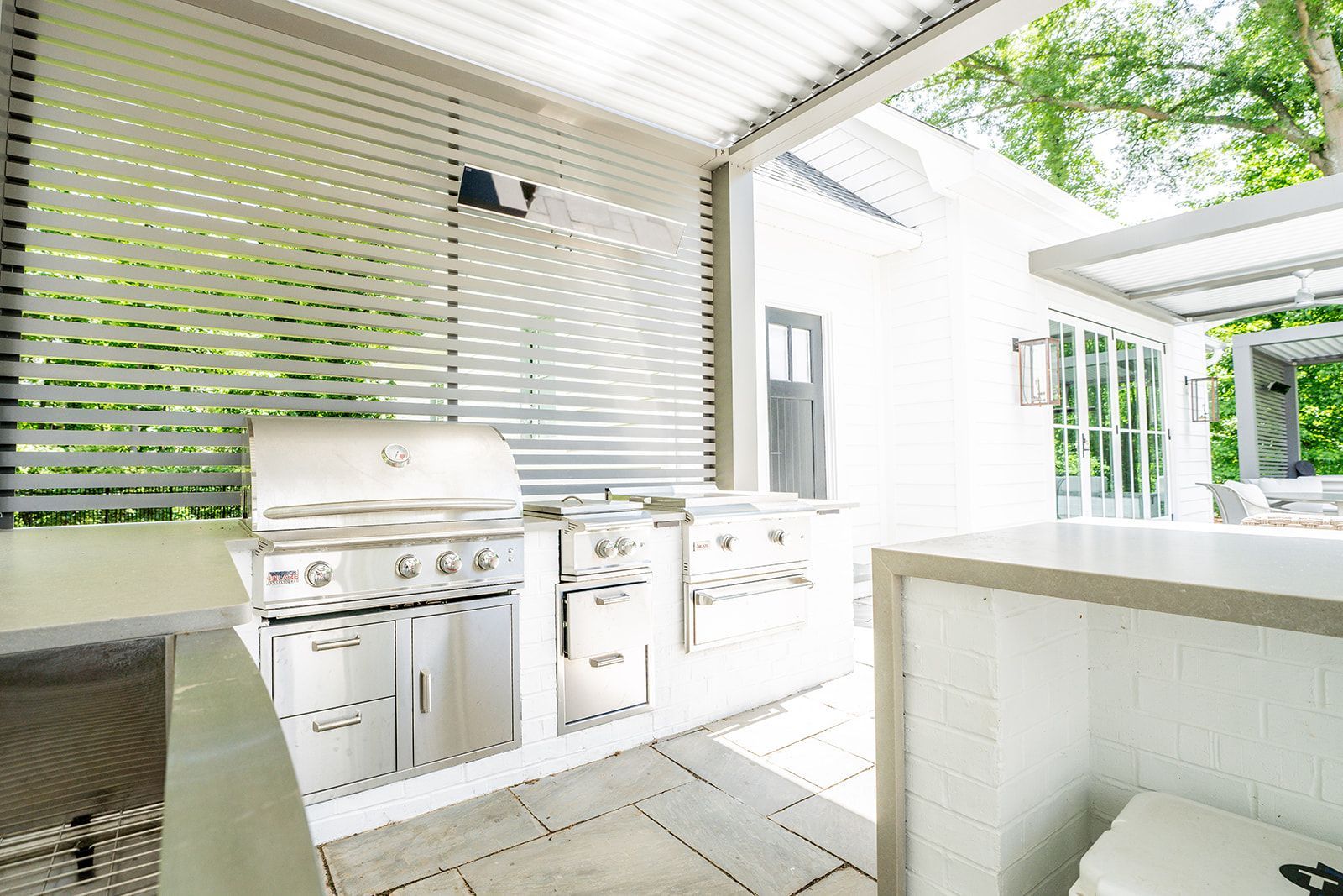 A large outdoor kitchen with a grill and a cooler.
