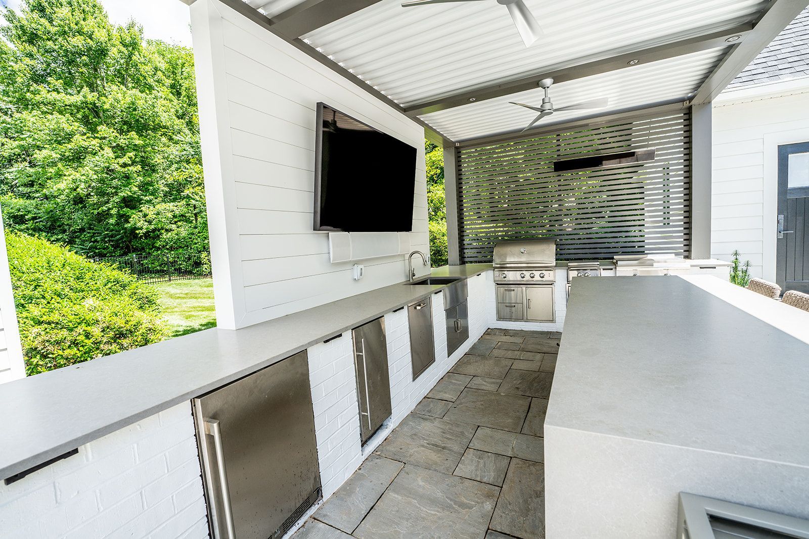 A large outdoor kitchen with a television on the wall.