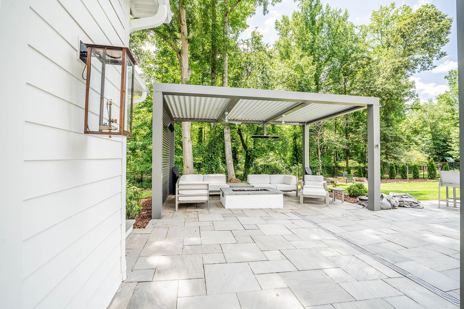 A patio with a pergola and a fire pit in the backyard of a house.