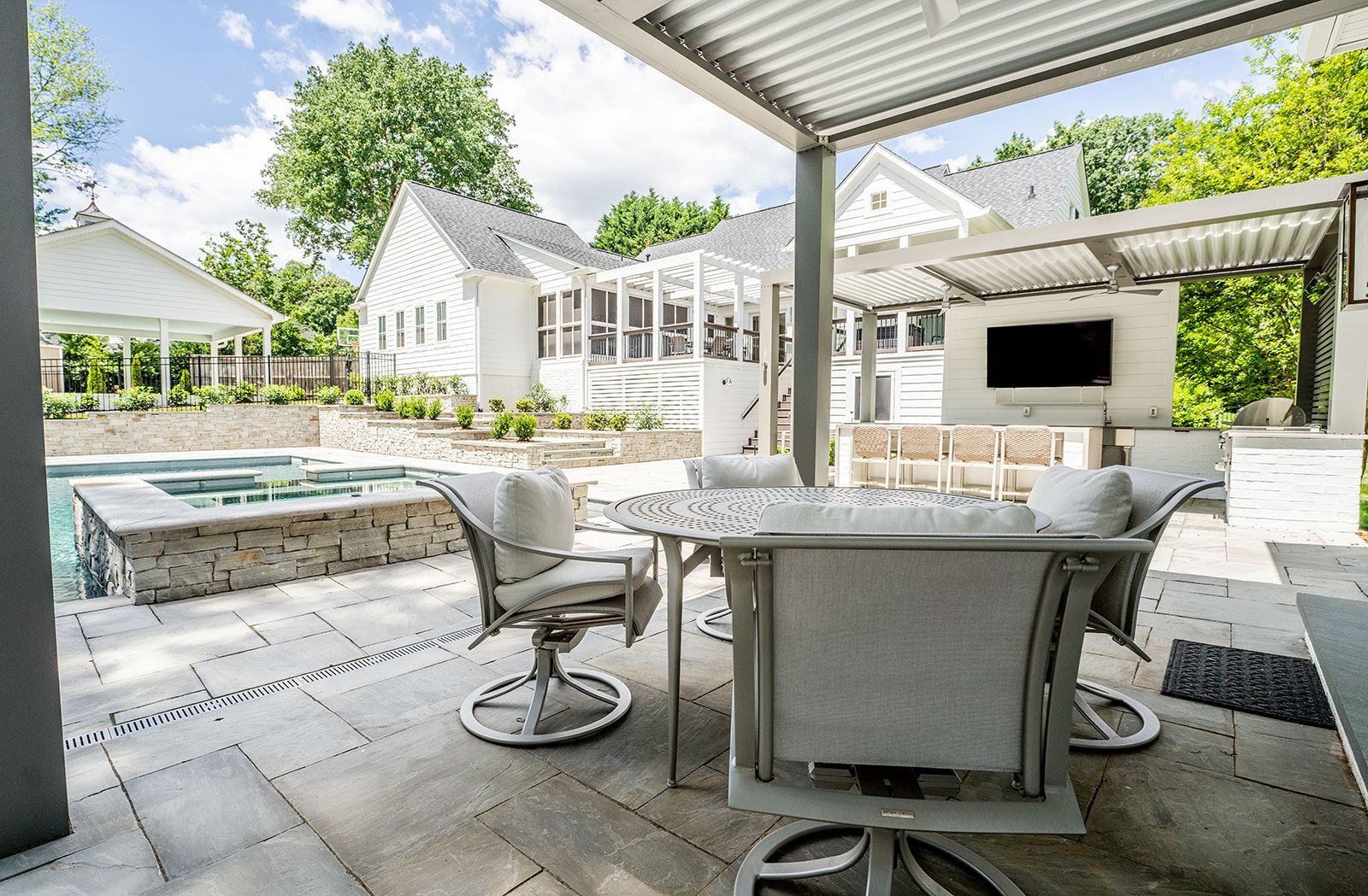 A patio with a table and chairs and a pool in the background.
