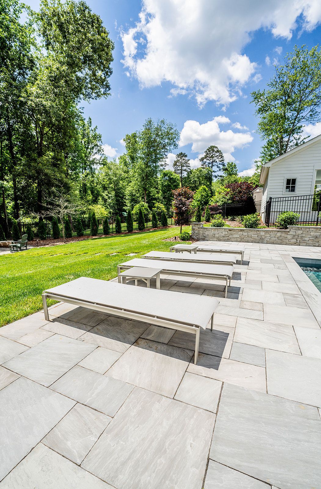 A row of lounge chairs are sitting on a patio next to a pool.