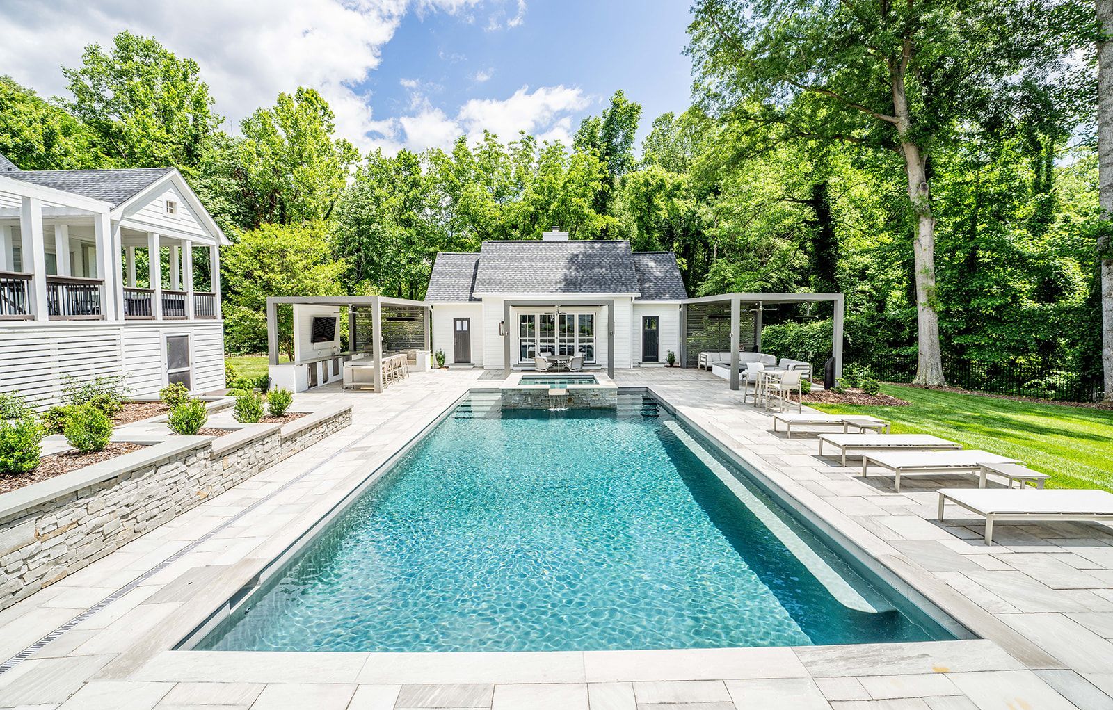 There is a large swimming pool in the backyard of a house.