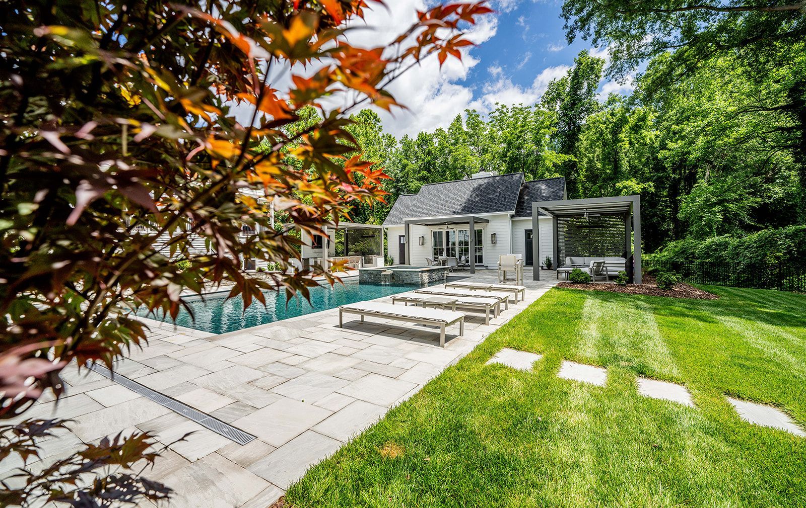 There is a large swimming pool in the backyard of a house.