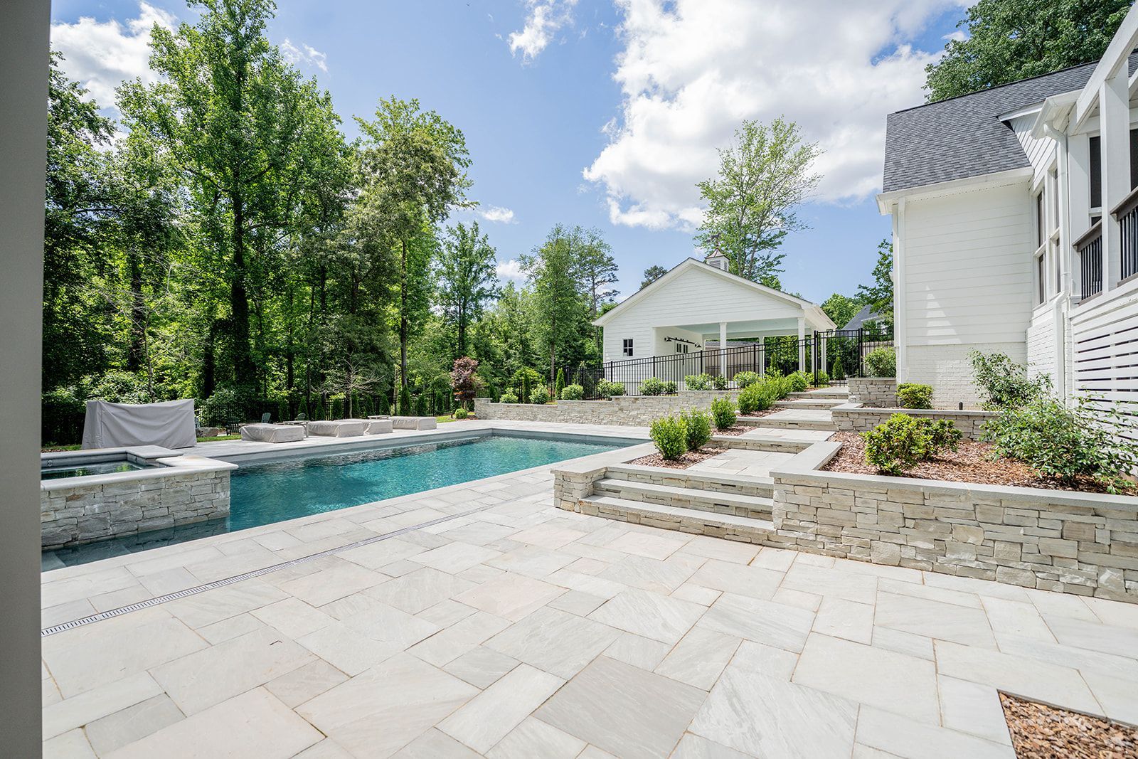 There is a large swimming pool in the backyard of a house.