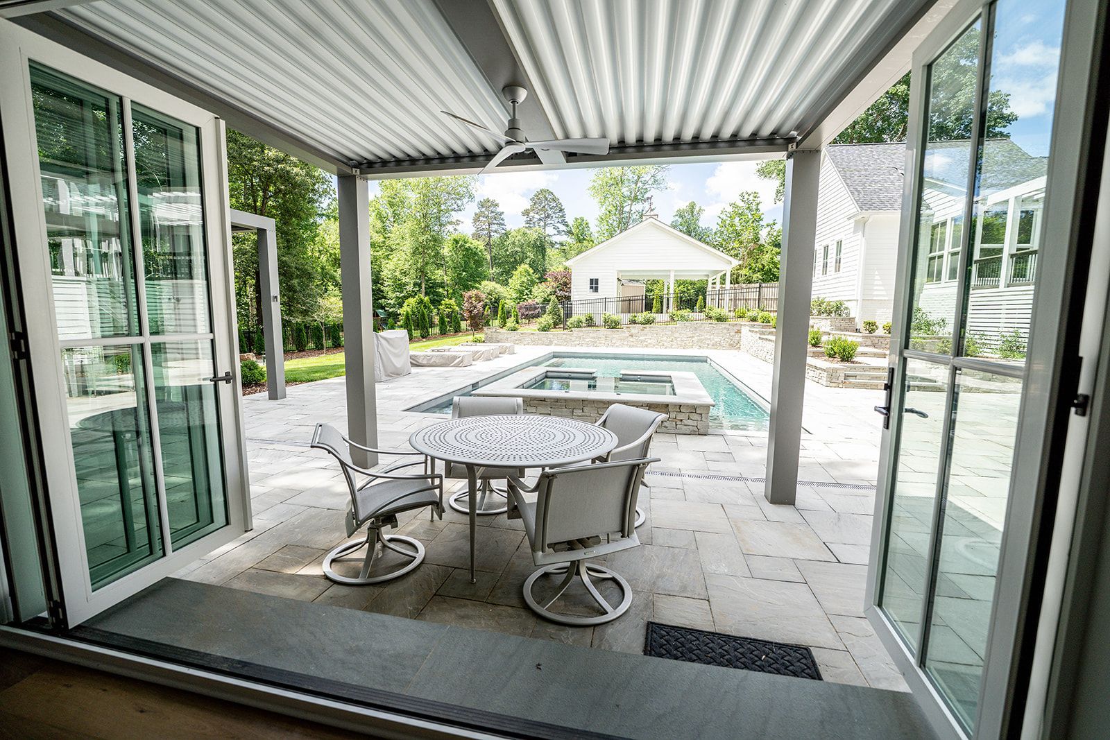 A patio with a table and chairs and a pool in the background.