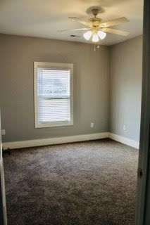 An empty bedroom with a ceiling fan and a window.