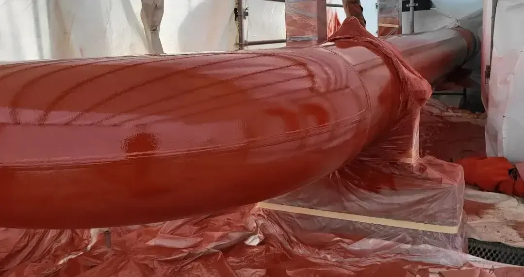 Protective red coating applied to an industrial pipe using precision spray techniques