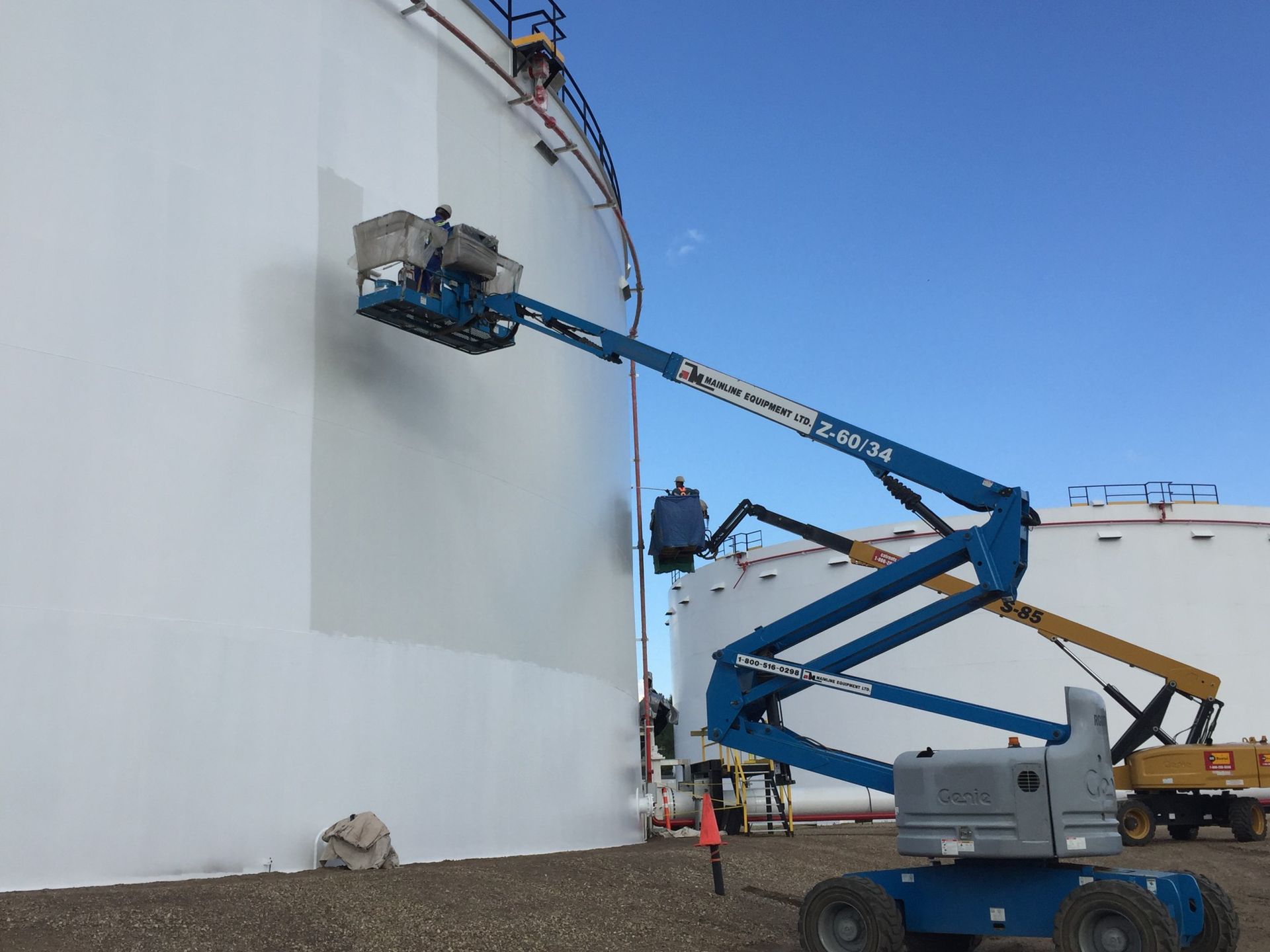 Protective white coating applied to large fuel storage tanks using boom lifts
