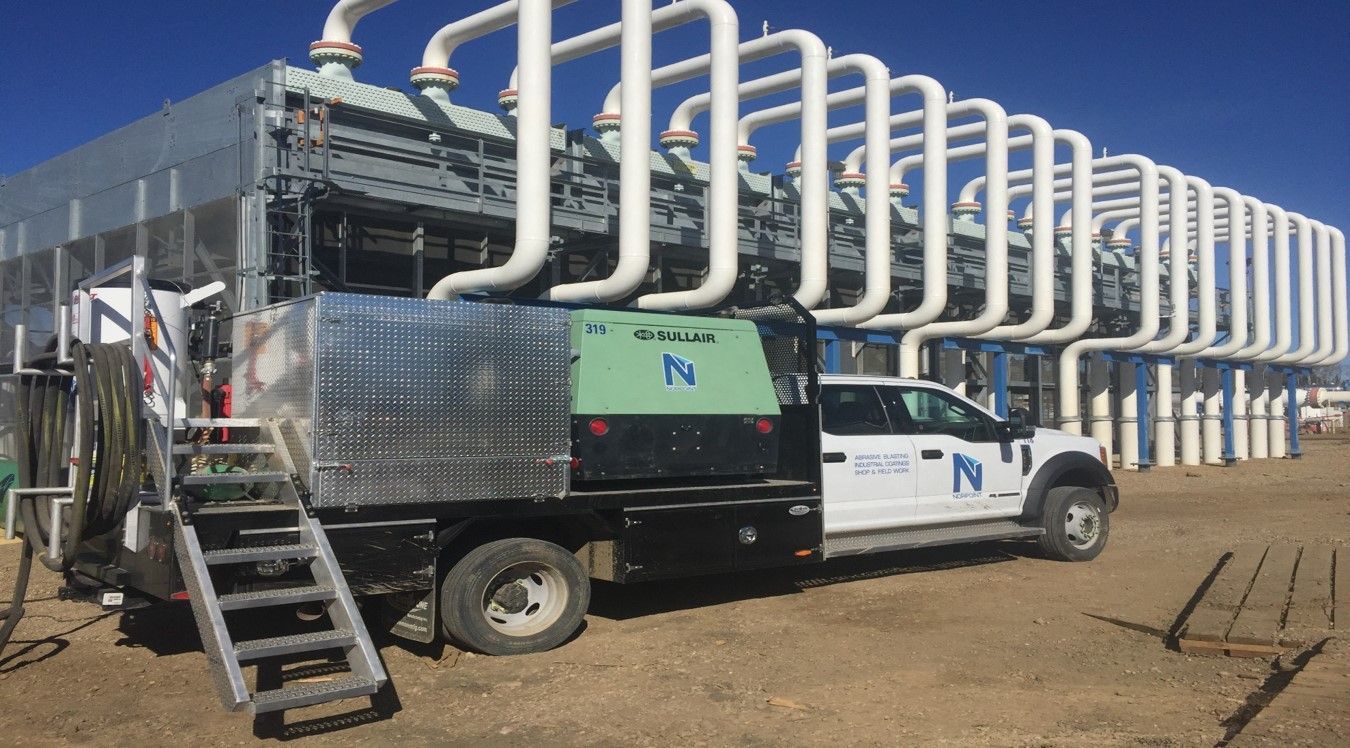 Norpoint vehicle carrying mobile coating equipment positioned beside a pipe system