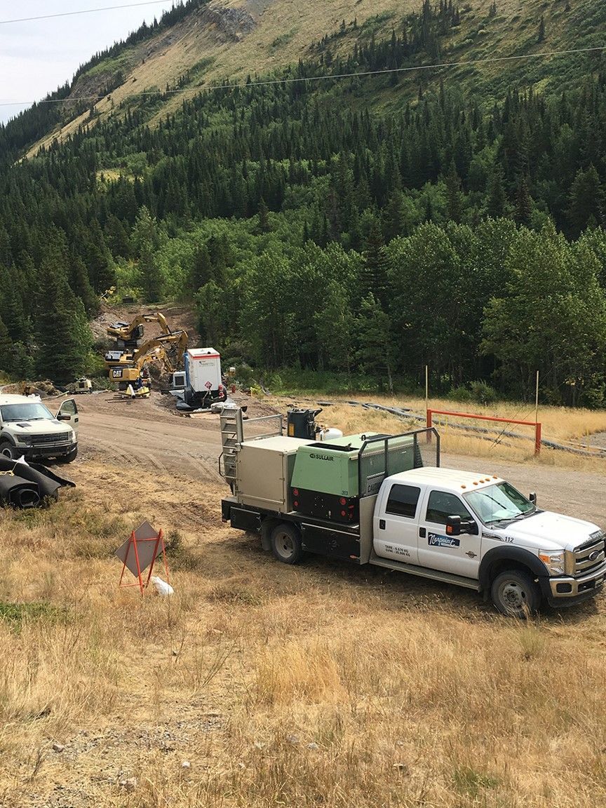 Forested project area with Norpoint truck and mobile coating system on rugged terrain