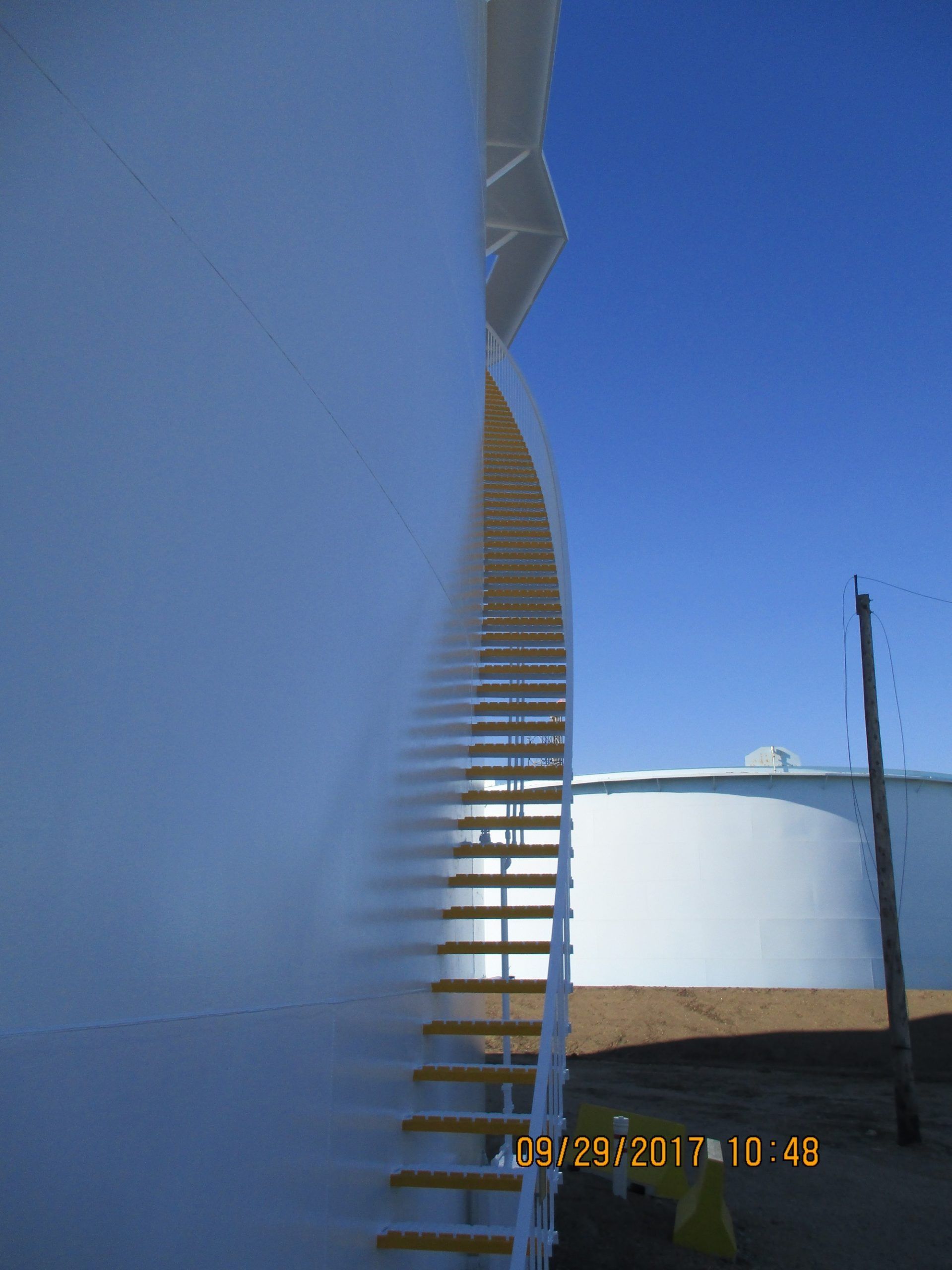 Large coated industrial tank with access staircase, showcasing seamless exterior coating finish