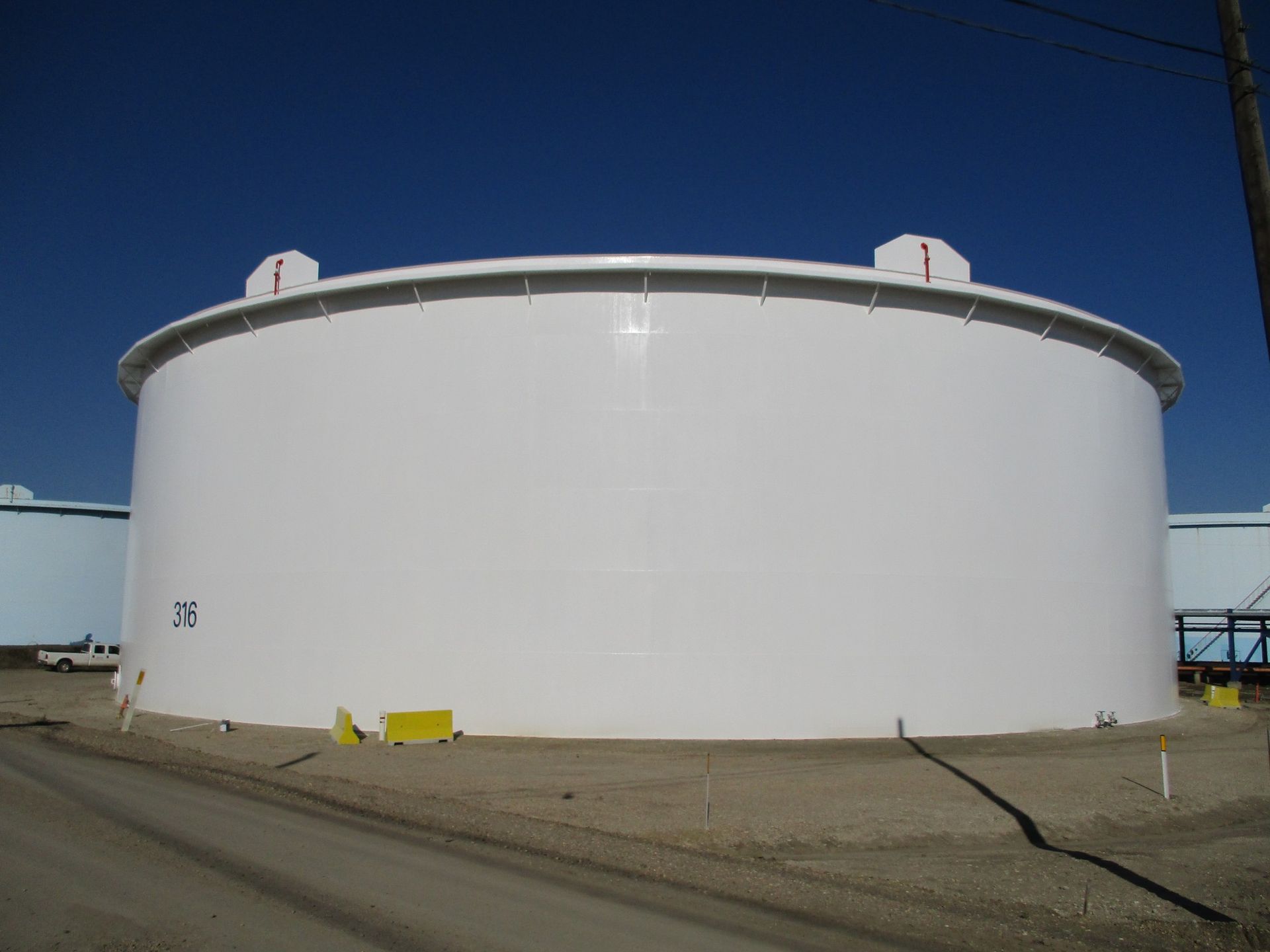Front view of a fully coated white storage tank with clear identification markings