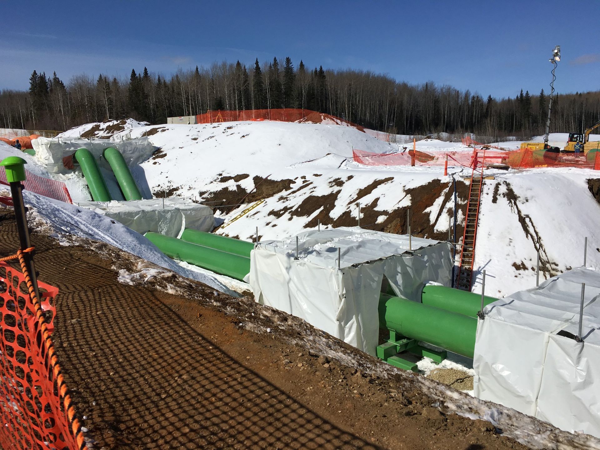 Winter construction site with green pipelines and protective coating systems in place