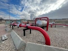 Outdoor facility showing red industrial pipes treated with corrosion-resistant coating