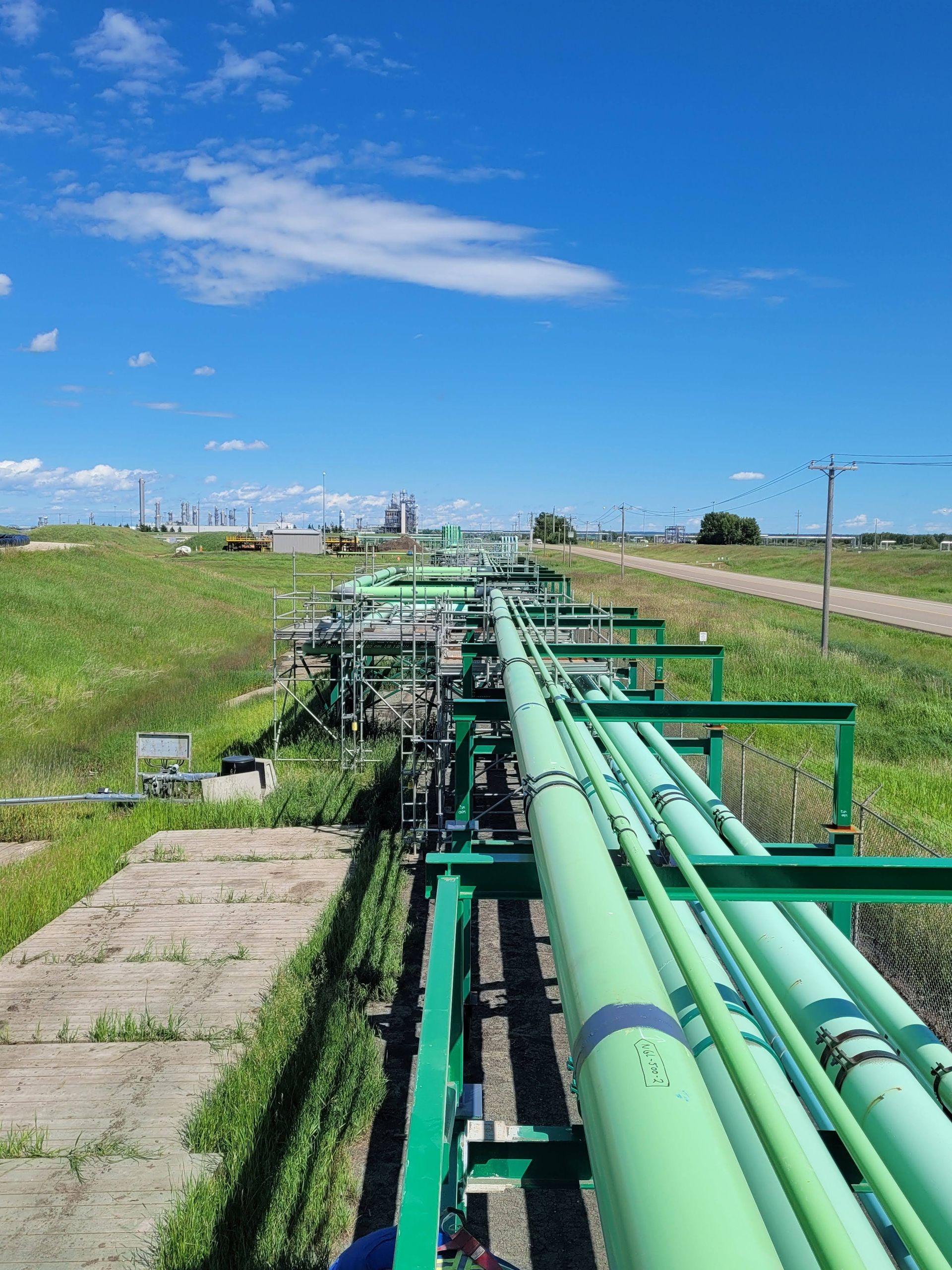 Extensive green-coated industrial pipelines running through an open field