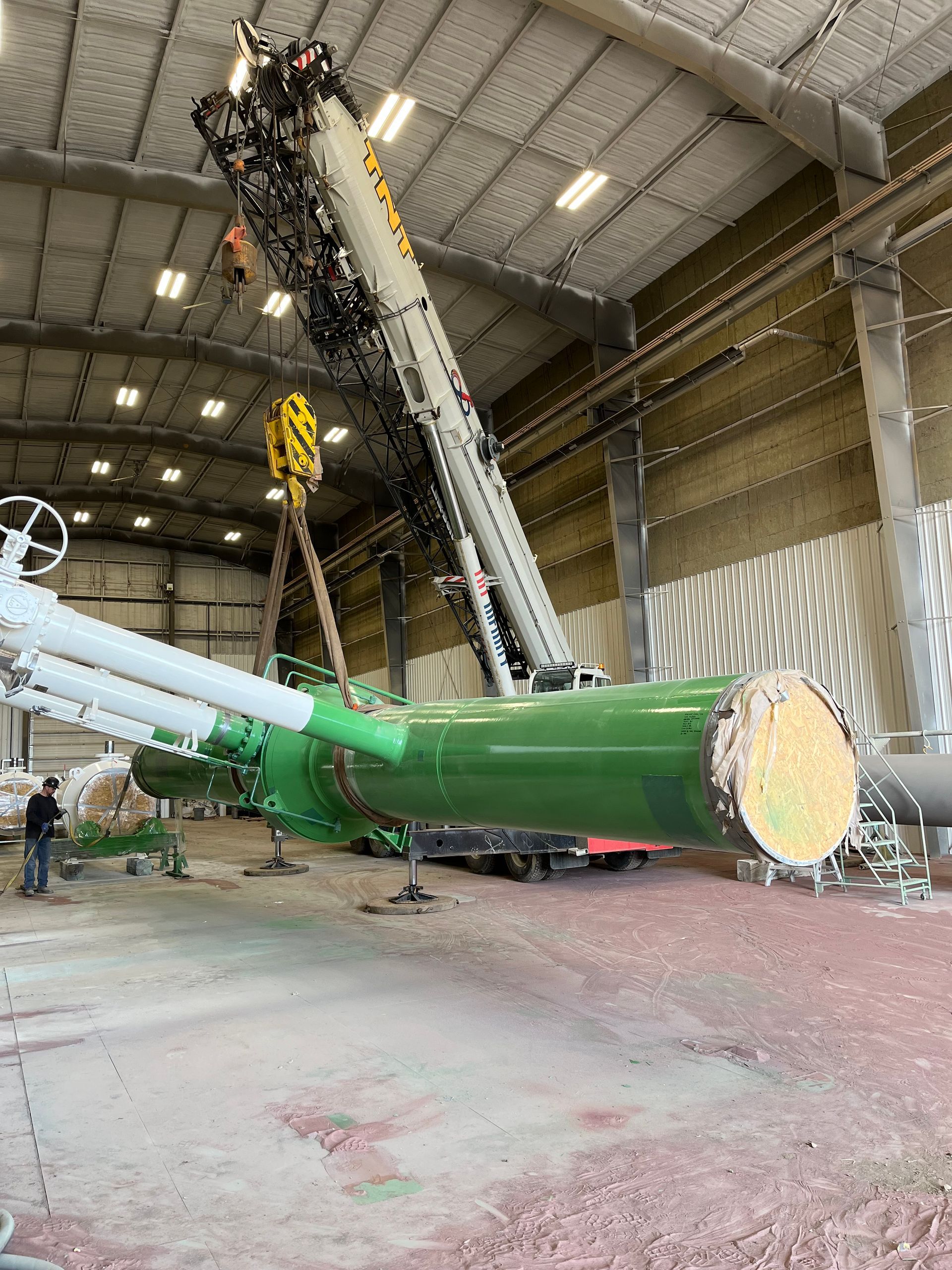 Heavy-duty green-coated pipe lifted by crane after undergoing comprehensive blast cleaning