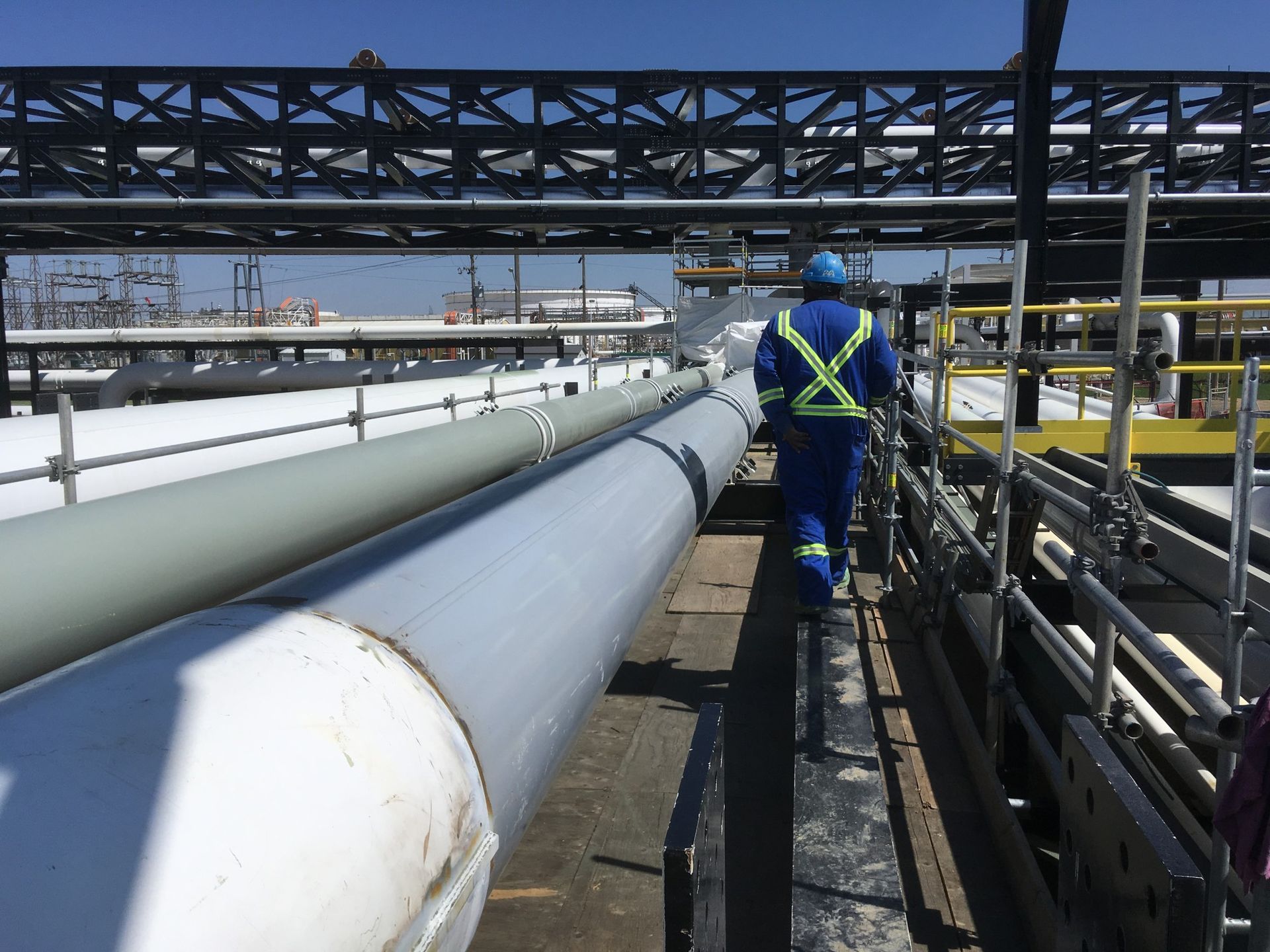 Worker inspecting industrial pipeline after coating application in high-access area