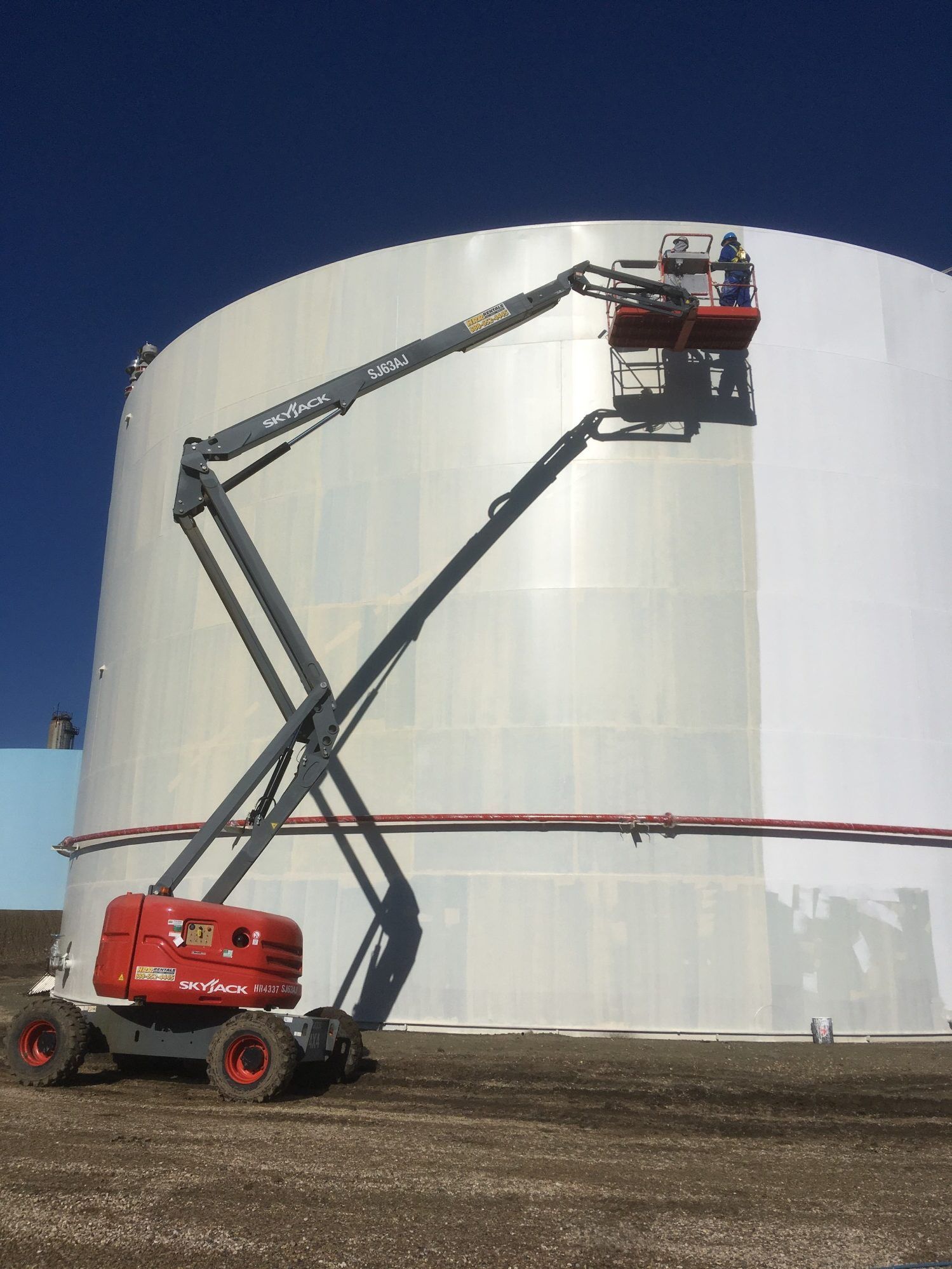 Industrial coating application on a large storage tank using a boom lift for high-access surface preparation and protective layering